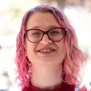 michelle profile Woman with pink hair smiling outdoors.
