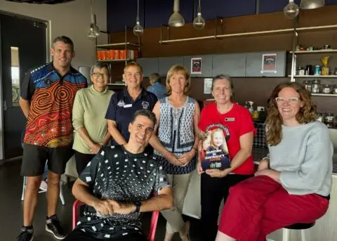 Group of happy people gathered in a bright café setting.