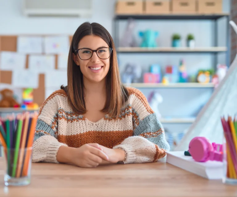 Smiling woman with glasses at creative workspace.